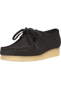 Svart mockaskor med rund tå, läder snörning framtill och lätt gummisula. Har synliga sömmar längs kanten.