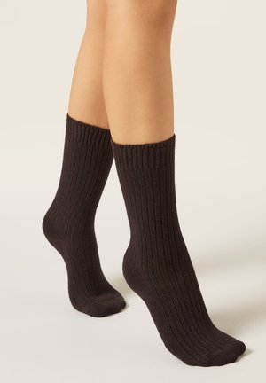 Calcetines negros acanalados hechos de tela suave, con rayas verticales y un borde vuelto en la parte superior, que llegan hasta la mitad de la pantorrilla, con una textura lisa.