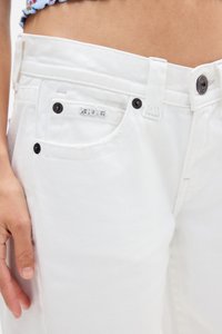 Vaqueros de mezclilla blanca con un diseño ajustado, que cuentan con acentos de botones negros, un acabado texturizado y una pequeña etiqueta de la marca en el bolsillo.