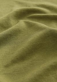Textile de couleur vert olive, présentant une texture douce et lisse avec un motif côtelé visible, se drapant doucement en plis.