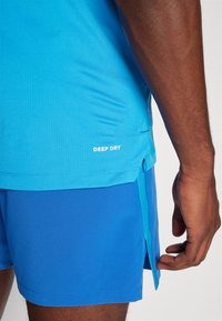 Short-sleeve blue athletic shirt made of breathable fabric with "DEEP DRY" printed at the side, paired with matching blue shorts.