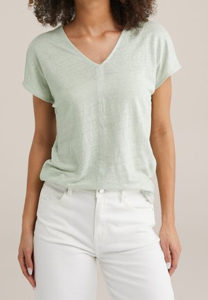 Lichtgroen T-shirt met korte mouwen en V-hals, gemaakt van zachte, gestructureerde stof. Draagt comfortabel met witte jeans, heeft een ontspannen pasvorm en fijne naaddetail in het midden.