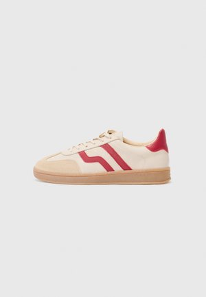 Beige sneakers with red stripes, rubber sole, and a mix of smooth and textured materials. Features a tan tongue and lacing system.