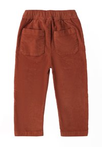 Rdzawoczerwone spodnie z korduroy z elastycznym paskiem w talii, dwiema tylnymi kieszeniami oraz prostym krojem nogawki. Pionowa faktura z żebrowania na całej powierzchni.