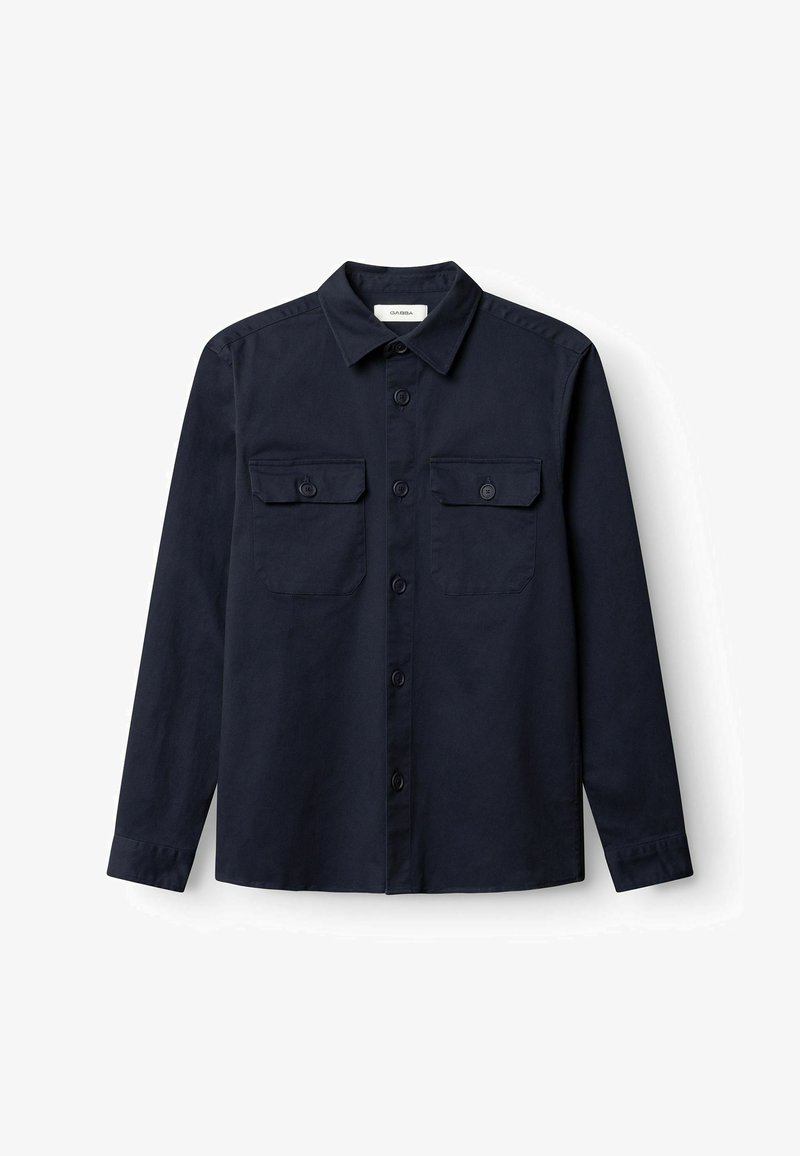 Chemise bleu marine à manches longues avec boutons, col, deux poches à rabat sur la poitrine avec boutons, et poignets boutonnés.