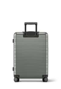 Valise rigide grise avec des rainures verticales, poignée noire extensible et quatre roues noires pour la mobilité. Forme rectangulaire compacte.