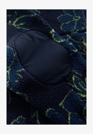 Fleecejack met een gestructureerde donkerblauwe stof en groene bladpatronen. Voorzien van een gladde, marineblauwe ellebooglap voor duurzaamheid en comfort.