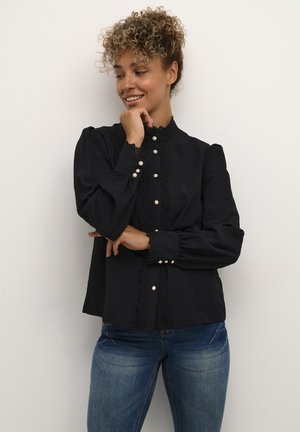 Zwarte blouse met hoge kraag, kantaccenten en parelknoopjes. Heeft opgezette mouwen en een ontspannen pasvorm met een gladde textuur.