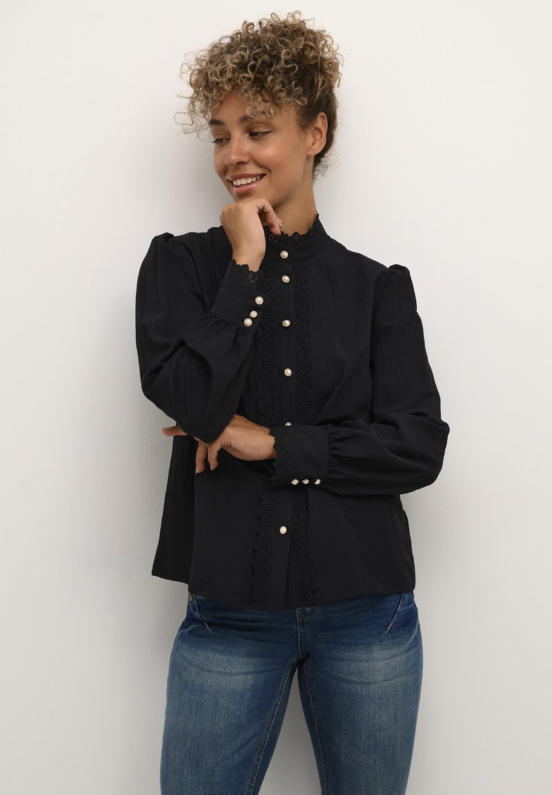 Black blouse with a high collar, lace accents, and pearl buttons. Features puffed sleeves and a relaxed fit with a smooth texture.