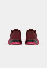 Pair of maroon and pink athletic shoes viewed from the back, featuring black accents and the "METCON" label on the heel.