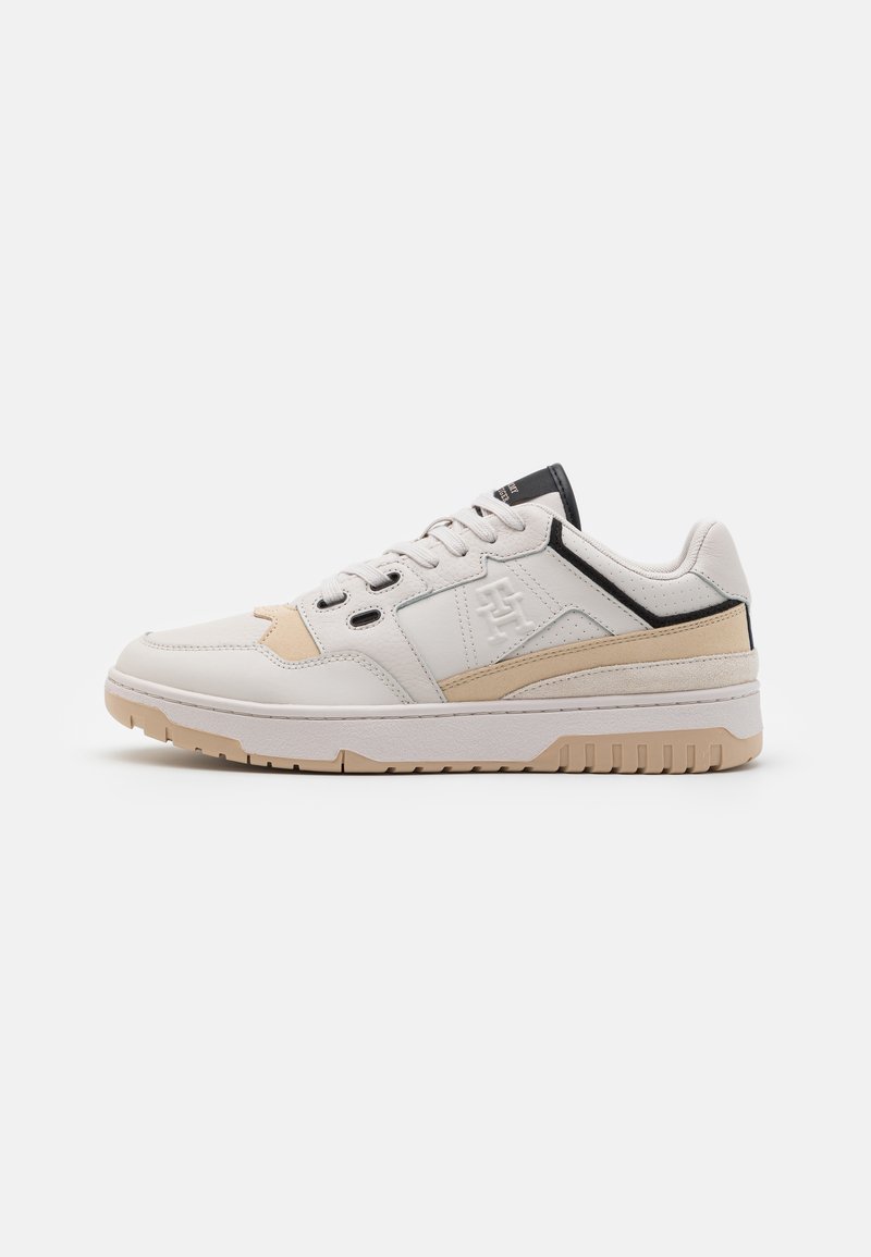 Sneakers bianchi in pelle con accenti marroni e neri, un design testurizzato e una soletta imbottita con modelli di battistrada visibili.