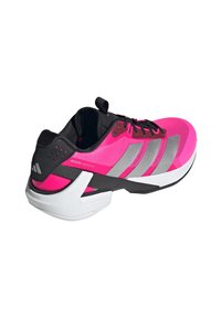 Kirkas vaaleanpunainen urheilukenkä mustilla yksityiskohdilla, hopea-raitaiset, valkoinen pohja ja "Adizero Ubersonic" -brändäys sivussa.