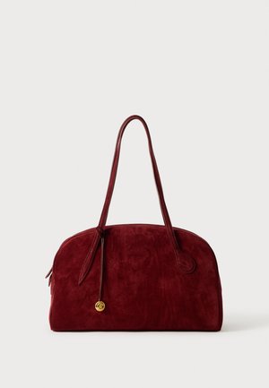 Bordeaux suède handtas met twee ronde handvatten, een gouden accentdetail en een gladde textuur. Het ontwerp is ruim en zacht afgerond.