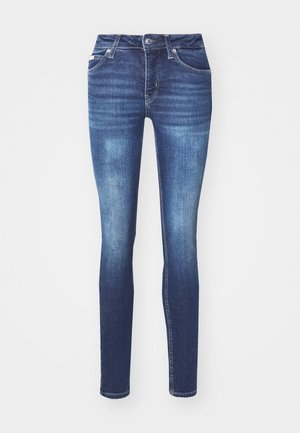 Tanke jeans v temnem pranju, z mednim pasom, petimi žepi in subtilnimi podrobnostmi bledenja na stegnih.