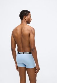 Svetlomodré boxerky s čiernym elastickým pásom s logom "PUMA", zobrazené zozadu na modeli. Hladký povrch.
