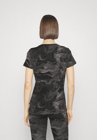 Camiseta negra de manga corta con un patrón de mármol gris en espiral, con cuello redondo y un ajuste cómodo. Textura de tela suave.