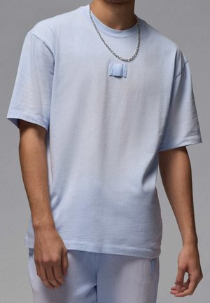 Lichtblauw katoenen T-shirt met een relaxte pasvorm, korte mouwen en een klein stofpatchdetail op de borst. Gecombineerd met bijpassende broek.