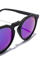 Černé sluneční brýle s ostrým designem, vybavené gradientními fialovými skly a matným povrchem. Výrazným detailem jsou zdůrazněné obroučky.