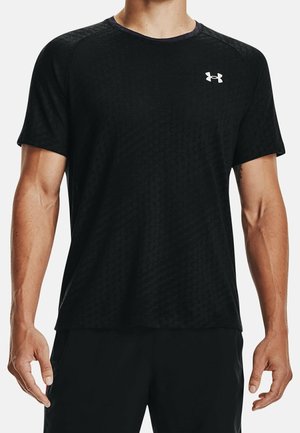 Mann trägt ein schwarzes kurzärmeliges Sport-T-Shirt mit weißem Under Armour-Logo auf der Brust und schwarze Shorts.