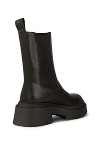 Svart läder ankelboot med ribbade elastiska sidopaneler och en tjock, robust sula. Kännetecknas av sin släta textur och moderna design.