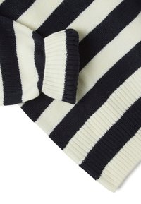 Pull en tricot avec des rayures alternées bleu marine et crème. Poignets et ourlet côtelés, avec une finition douce et texturée.