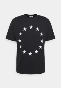 Černé bavlněné tričko s kruhovým vzorem bílých hvězd, představujících Evropskou unii, umístěným na přední straně.