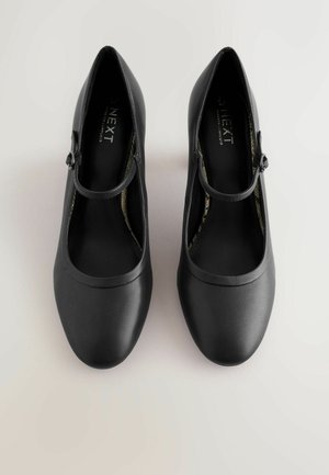 Mustad Mary Jane’i jalanõud, millel on sile, matt viimistlus, ümar varvas ja õhuke rihm ringikujulise pannaletailiga.