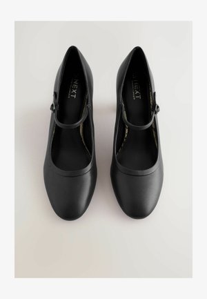 Melnas Mary Jane kurpes ar gludu, matētu apdari, apaļu purngalu un plānu siksniņu ar apaļu sprādzes detaļu.