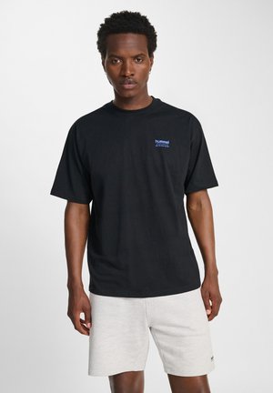 Zwarte katoenen t-shirt met korte mouwen, met een klein blauw logo op de borst. Gecombineerd met lichtgrijze shorts.