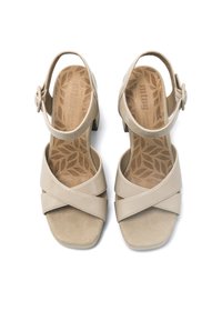 Sandalias de mujer en color beige, con punta abierta y tiras entrecruzadas, hebilla en el tobillo, tacones bajos en bloque y un patrón de hojas en las plantillas de cuero.