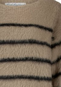 Pull en beige moelleux avec des rayures horizontales noires et une étiquette de col visible indiquant "Red Button."