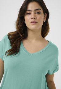 Turquoise v-neck t-shirt with short sleeves, made of soft fabric. Features a relaxed fit and smooth texture with minimal detailing.
