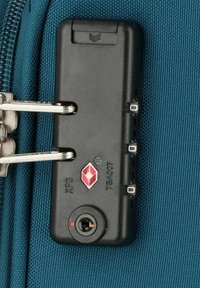 Zwart TSA-slot met een combinatie-draaiknop op een teal-kleurige koffer. Bevat een sleutelgaten en een rood diamantlogo. Rits gedeeltelijk zichtbaar.