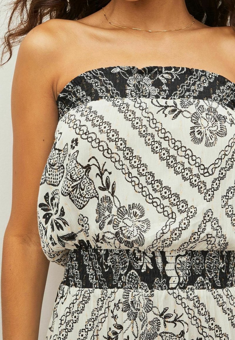Trägerloses Kleid mit schwarz- und cremefarbenem Blumendruck, strukturiertem Stoff, gerafftem Taillenbereich und aufwendigen Musterdetails.