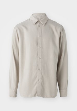 Beżowa koszula z długim rękawem wykonana z miękkiego materiału, z zapięciem na guziki z przodu, klasycznym kołnierzykiem i mankietami z zaokrąglonymi rogami.