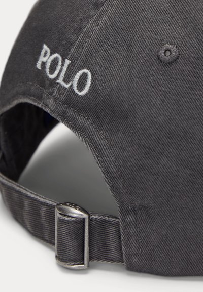 Temno siva baseball kapa z belo vezenino "POLO" in nastavljivim kovinskim trakom na zadnji strani.