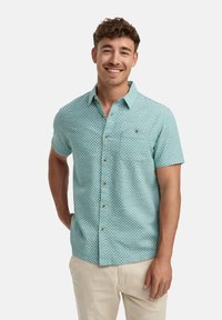 Korte mouwen, lichtblauw shirt met een klein wit geruit patroon, button-down kraag en borstzak. Voorzien van bronzen knopen.