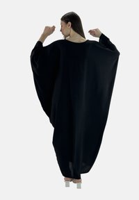 Czarna,oversize'owa kaftan z szerokimi rękawami nietoperzami, wykonany z miękkiej, płynącej tkaniny. Posiada szeroki dekolt i luźny, komfortowy krój.