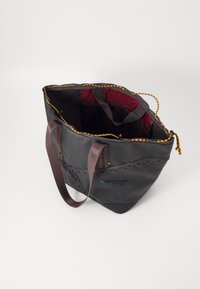 Sac fourre-tout noir avec un intérieur bordeaux, doté de deux anses en tissu, d'un bord festonné et d'un haut à cordon de serrage. Comprend une poche intérieure en maille.