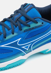 Scarpa da ginnastica blu con tomaia in mesh, design testurizzato e accenti sintetici. Presenta un'intersuola bianca e una suola in gomma con modelli di grip.