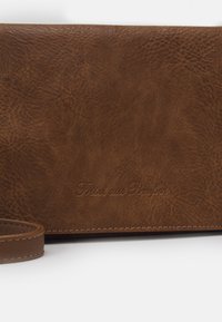 Brązowy skórzany portfel o fakturowanej powierzchni. Posiada wytłaczany napis „Fritz aus Preußen” oraz odpinany skórzany pasek.