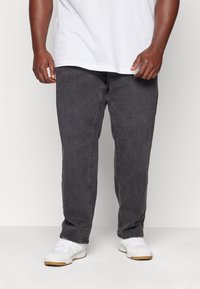 Hallid denim püksid sirge lõikega, millel on peen tekstuur, viis taskut ja klassikaline tõmblukk ning nööpidega sulgemine.