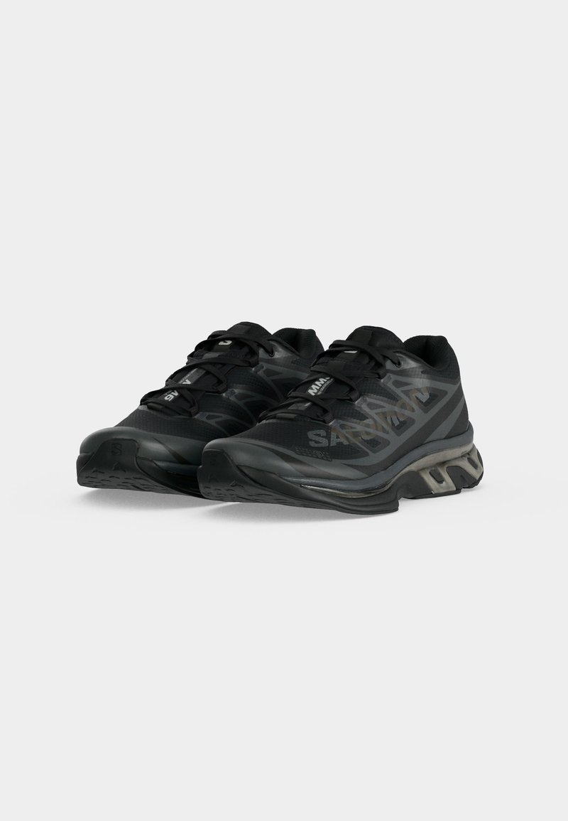 Pair of black Salomon running shoes with geometric side patterns and cushioned soles, positioned on a white background.