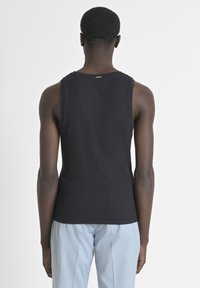 Camiseta sin mangas negra con textura acanalada, escote redondo y dobladillo recto. Diseño minimalista sin marcas visibles ni adornos.