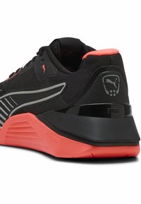 Sort og koral atletiksko med mesh-overdel, gummisål, reflekterende detaljer og tekstureret hæl. Har Puma-logo og "FUSE" branding.
