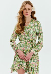 Kvetinové šaty v zelenom prevedení, s ružovými a žltými kvetmi. Dlhé rukávy, volánový lem a opasok na viazanie pre úpravu veľkosti.