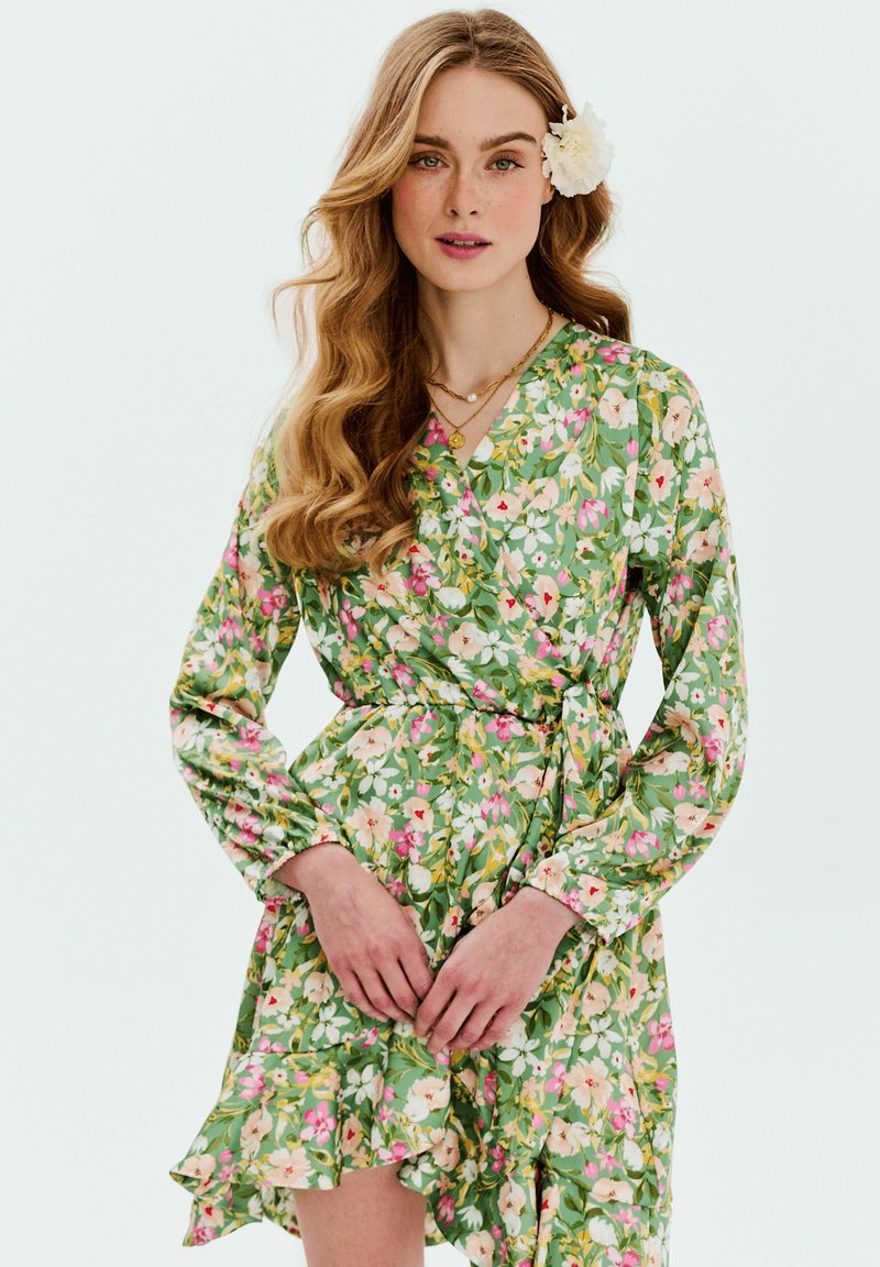 Kvetinové šaty v zelenom prevedení, s ružovými a žltými kvetmi. Dlhé rukávy, volánový lem a opasok na viazanie pre úpravu veľkosti.