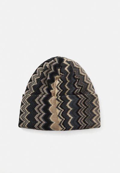 Căciulă tricotată cu model zigzag în tonuri de negru, bej și gri, plasată pe un fundal alb.