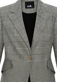 Tarkastettu bleiseri, jossa on musta-valkoinen kuviointi, yksittäinen nappisulku oranssilla yksityiskohdalla ja klassinen kauluskotelo.