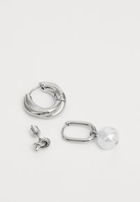 Sølv hoop øredobber med en vridd design, ledsaget av en perle-accentuert dråeøredobb og en liten stud øredobb.